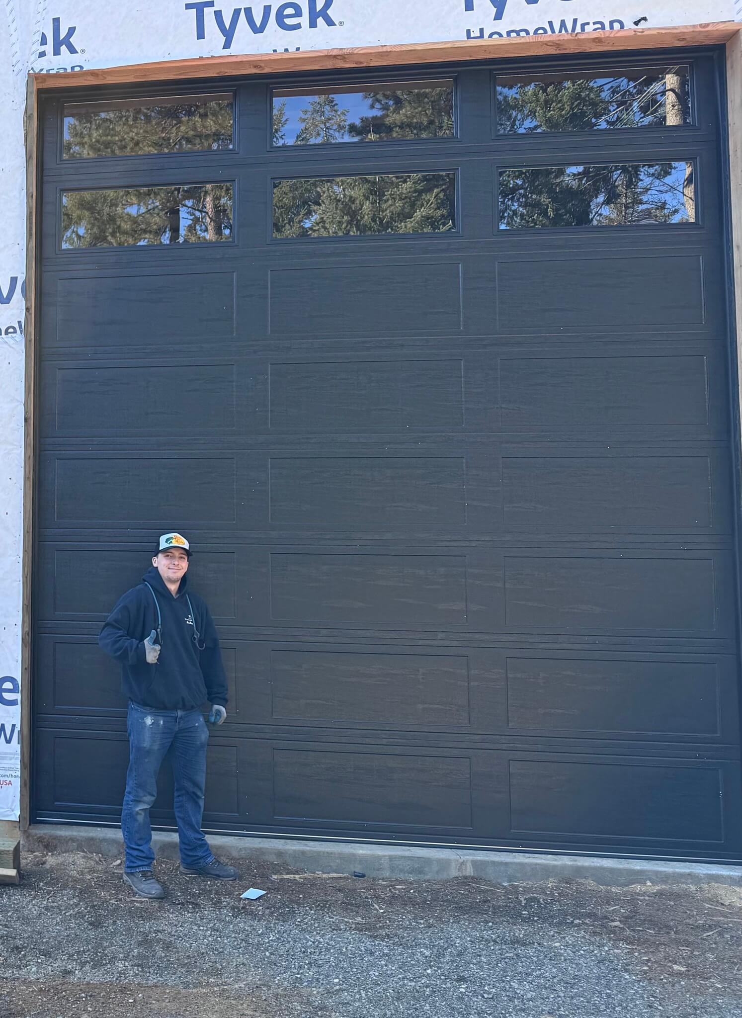 Blaine, an employee, standing in front of a tall, dark garage door